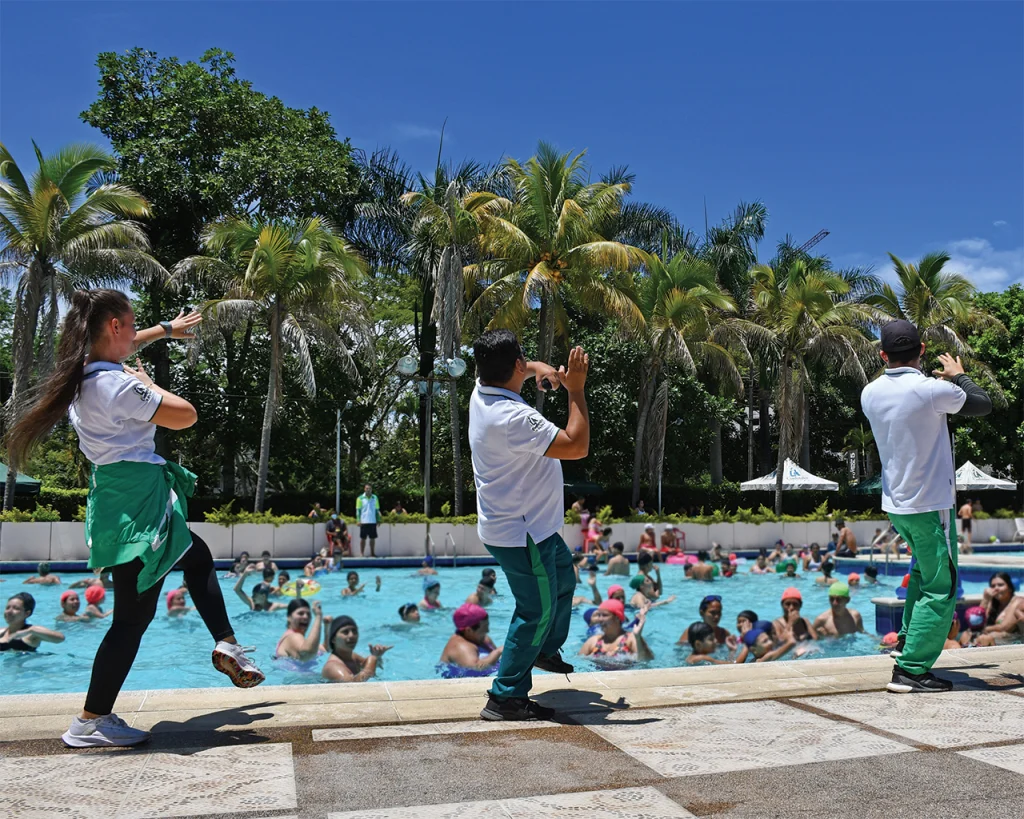 Recreadores haciendo coreografía para un gran grupo bañistas en piscina