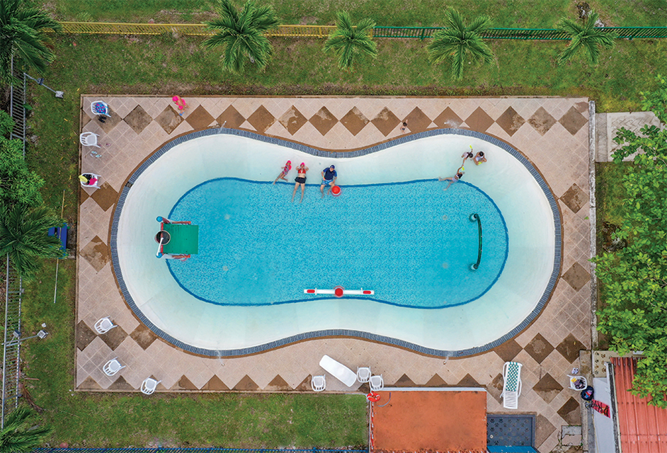 Vista aérea de piscina con personas sentadas al borde