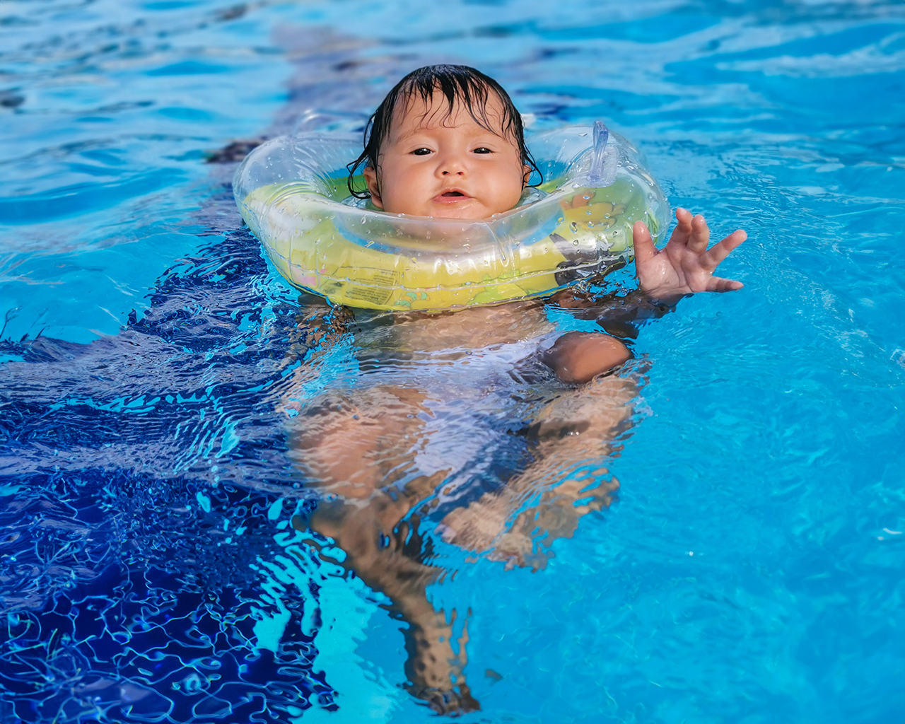 Bebé con flotador nadando en piscina