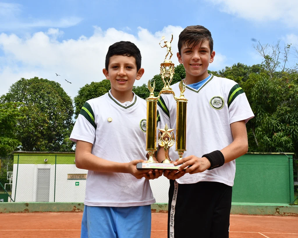 2 niños levantando trofeo de campeones de la categoría deporte tenis de campo