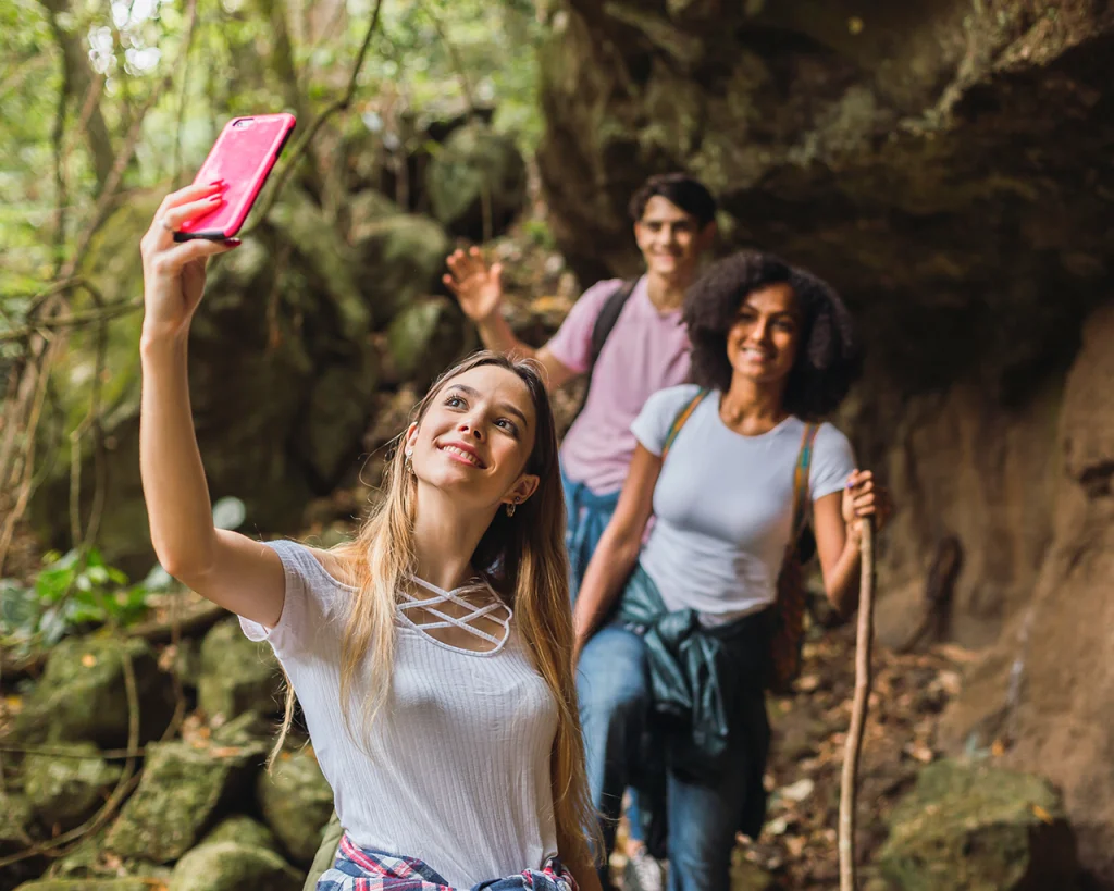 Personas caminando en sendero del bosque mientras se toman foto con celular inteligente