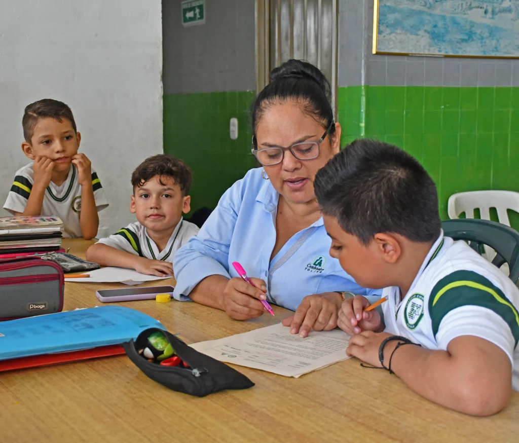 Profesora enseñando cuaderno a alumnos de colegio y escuela
