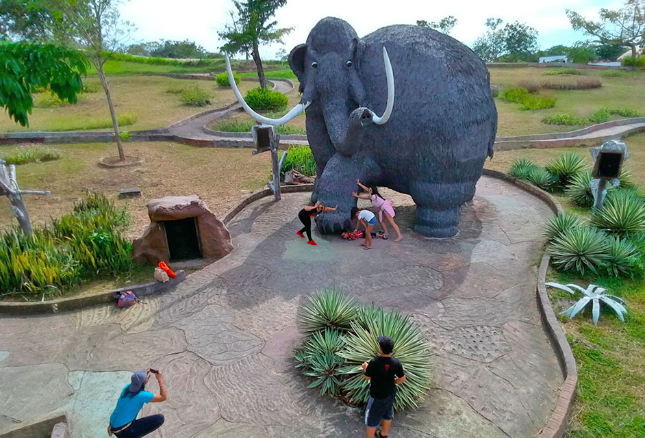 Familia posando para foto al lado de estatua de mamut