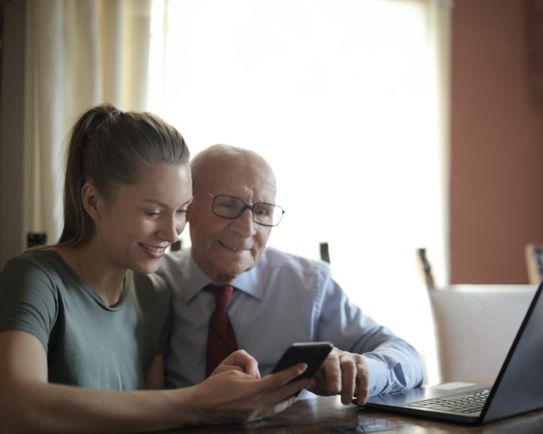 Mujer sonriente enseñando celular inteligente a hombre de la tercera edad sonriente