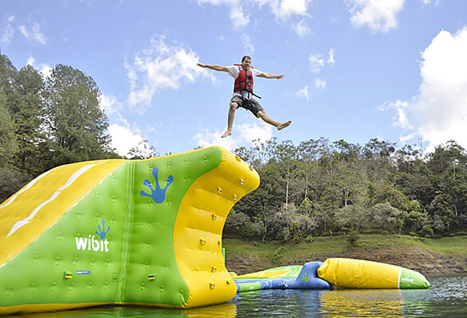 Hombre saltando al agua impulsado por gran colchón inflable