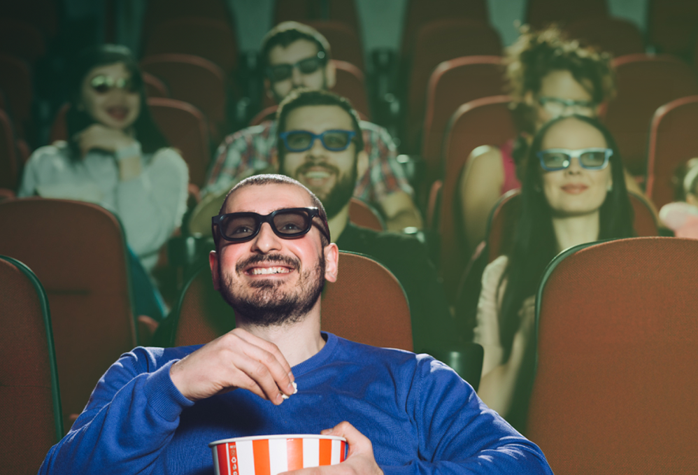 Hombre disfrutando película en cinema, mientras come palomitas de maíz.