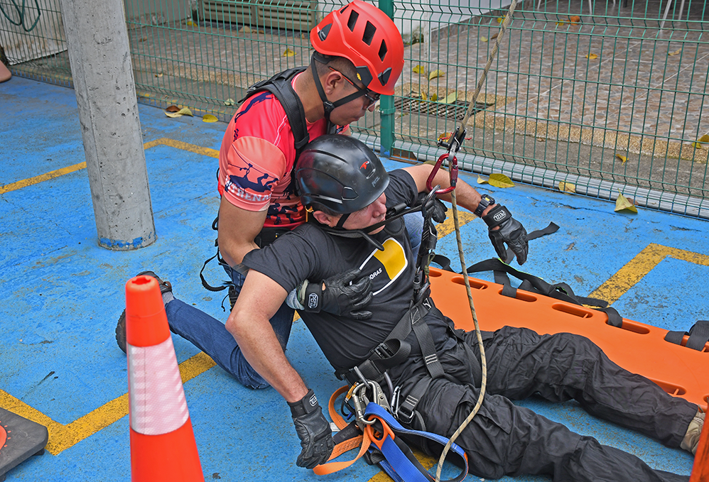 Hombre con equipo de seguridad asistiendo a otro hombre en centro de entrenamiento de alturas