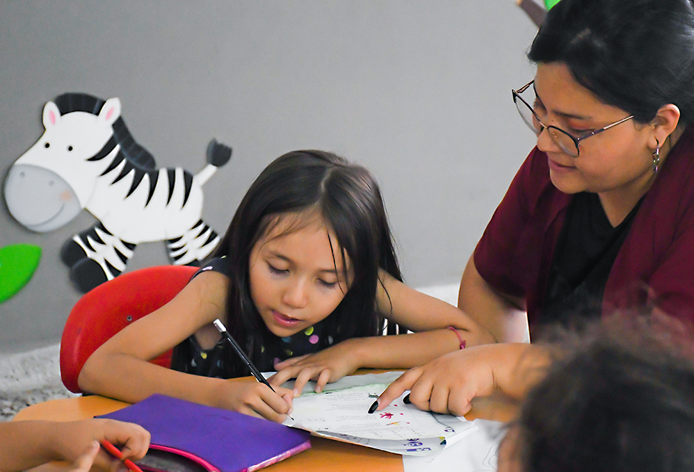 Niña haciendo trabajo de refuerzo escolar orientada