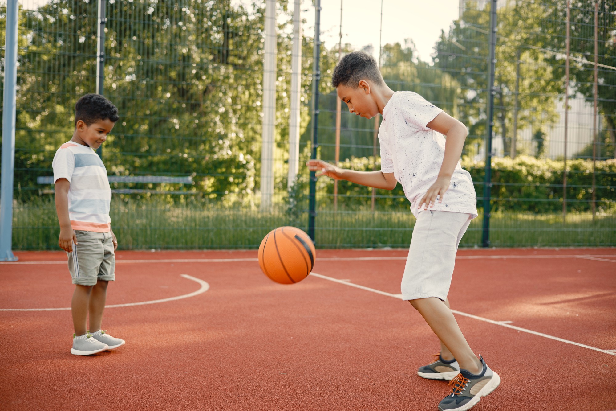 Dos niños jugando baloncesto en una cancha abierta